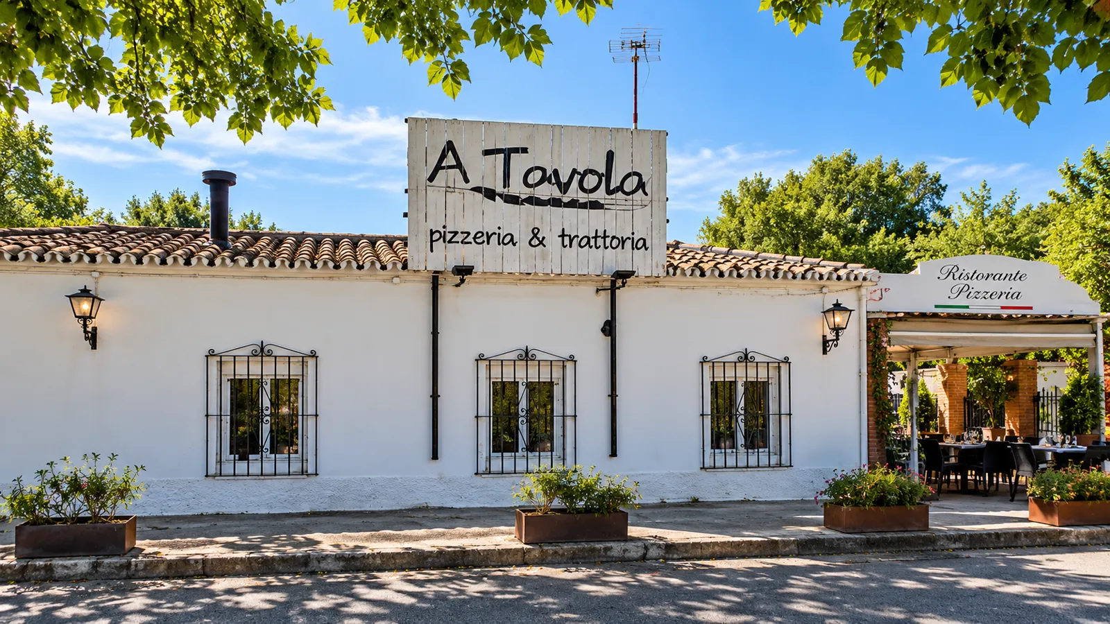Fachada blanca de A Tavola con su letrero de madera y la entrada a la terraza