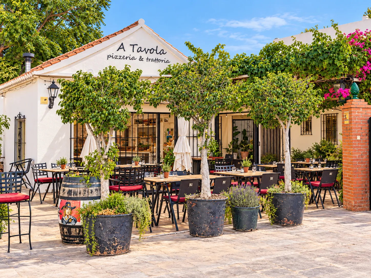 Terraza de A Tavola con mesas, árboles en macetas y buganvillas